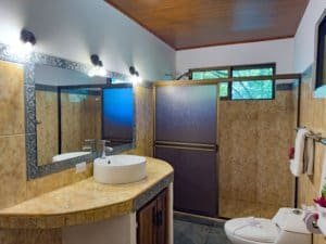 Costa Rican bathroom with shower, sink, and decorative tiles.