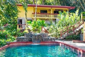 Beautiful pool with waterfall and villa in lush tropical setting.