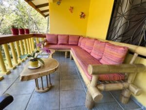 Balcony with pink cushioned wooden sofa and small table in Dominical Costa Rica.