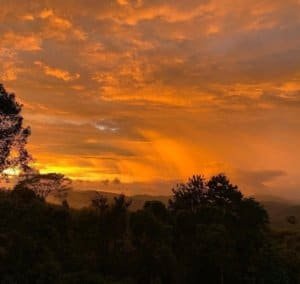 Beautiful sunset with orange and yellow hues over lush mountain landscape in Costa Rica.