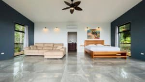 Spacious bedroom with partial ocean view, modern decor, and large windows in Dominical.