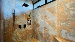 Modern shower with stone walls and rainfall showerhead in Costa Rica estate.