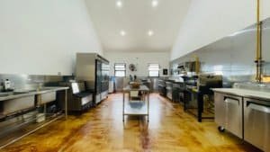 Spacious commercial kitchen with modern appliances and wooden floors.