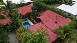 Two villas with red roofs, swimming pool, and lush tropical garden in Dominical.