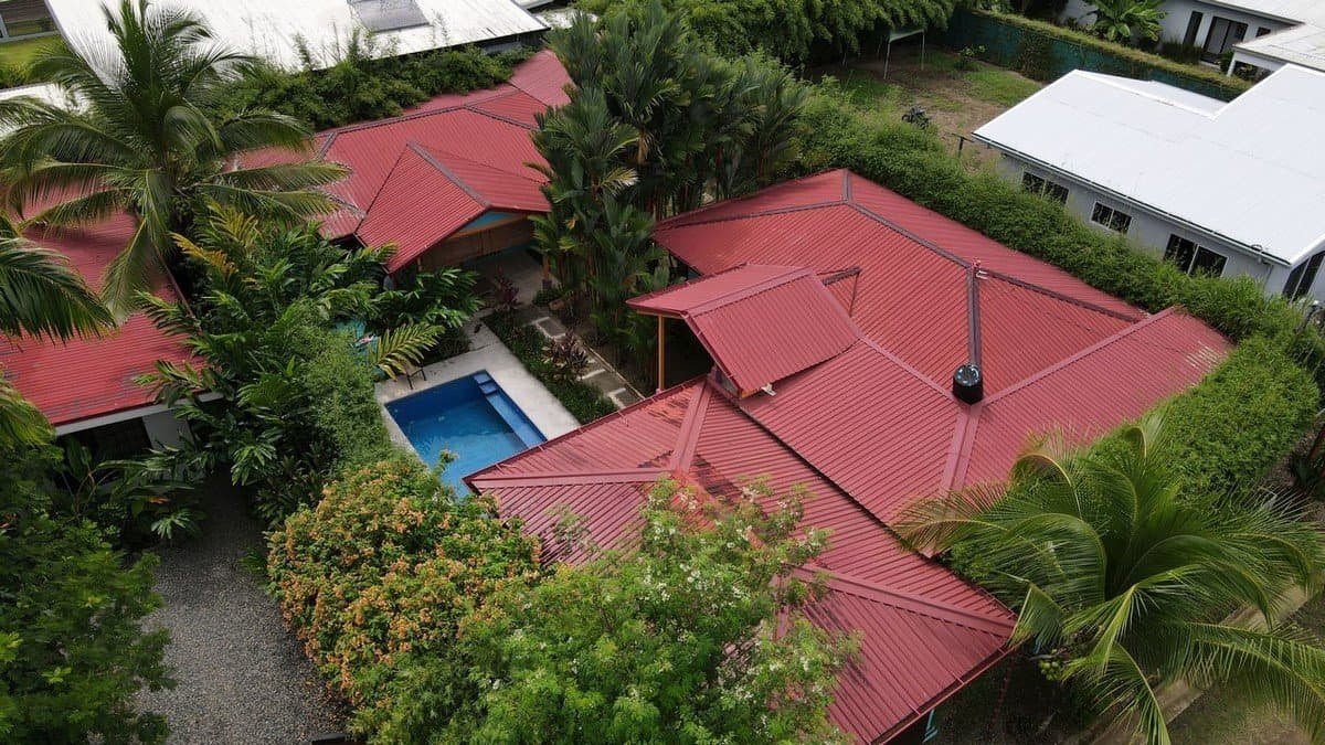 Two villas with red roofs, swimming pool, and lush tropical garden in Dominical.