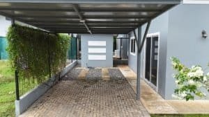 Covered driveway with modern house and garden in Dominical.