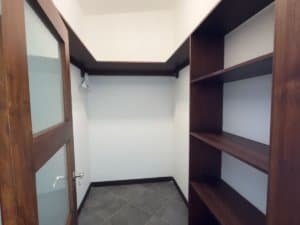 Large walk-in closet with wooden shelves and door in Costa Rica property.
