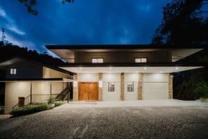 Modern luxury estate with illuminated facade and scenic surroundings.