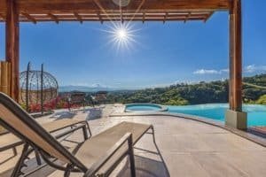 Infinity pool with mountain views and sunlit sky in Dominical.