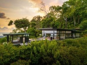 Modern luxury home with panoramic ocean views and lush greenery.