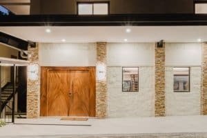 Modern gated community entrance with wooden doors and stone accents.