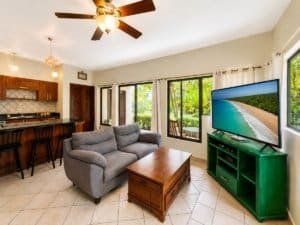 Living room with sofa, TV, and view of lush greenery in Dominical.
