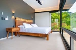 Contemporary bedroom with large glass windows overlooking lush tropical landscape.