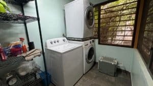 Laundry room with washer, dryer, and storage shelves in Dominical.