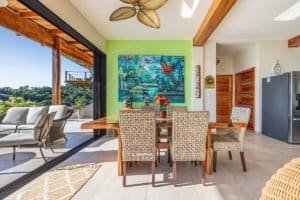 Interior of a Costa Rican home with a dining table, colorful art, and outdoor balcony.