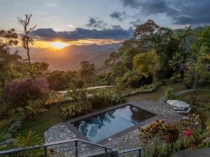 Panoramic view of mountain retreat with pool and sunset in Dominical.