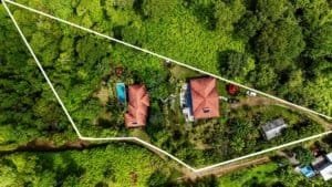 Aerial view of a property with a house, boutique lodge, pool, and lush greenery in Dominical.
