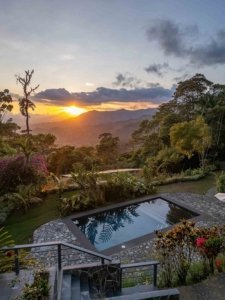 Scenic view of sunset over mountains from luxury retreat with pool and garden.