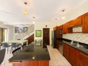 Modern kitchen with wooden cabinets, black countertops, and dining area in Dominical.