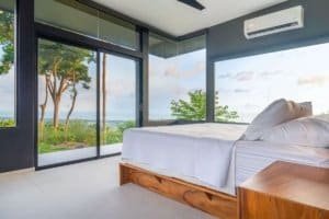 Modern bedroom with panoramic ocean views and glass walls in Dominical.