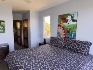 Interior of bedroom with patterned bedding and vibrant wall art.