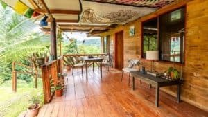 Cozy mountain home porch with wooden furniture and lush greenery.