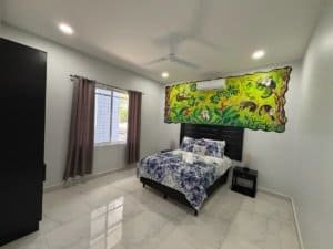 Bright bedroom with jungle-themed wall art and large window in Dominical.