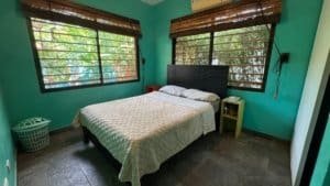 Bedroom with two windows, bed, and nightstand in Costa Rica.