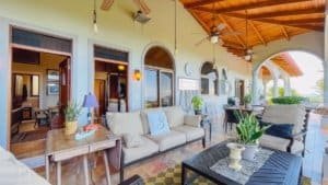 Balcony of tropical hacienda with seating, plants, and ocean view in Costa Rica.