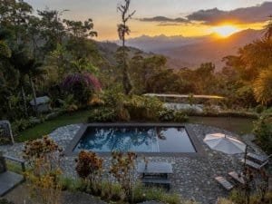Scenic mountain view with pool, lush greenery, and sunset in Dominical.