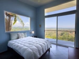 Bright bedroom with ocean, mountain, and sunset views in Dominical.