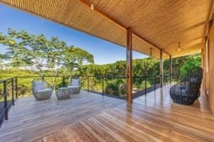 Spacious balcony with mountain views, wicker chairs, and lush greenery in Dominical.