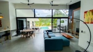 Spacious living room with large glass doors opening to pool and tropical garden.