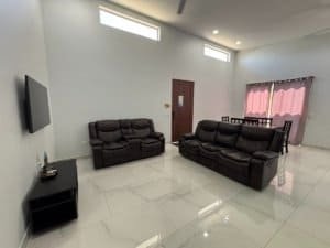 Spacious modern living room with black leather sofas and a wall-mounted TV.
