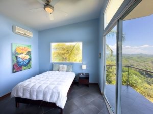 Bedroom with ocean and mountain views, balcony, and modern decor in Dominical.