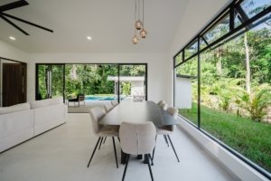 Bright dining area with large windows overlooking lush greenery in Costa Rica.