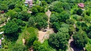 Aerial view of lush green land with mountain views and access roads.