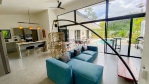 Bright living room with large windows, blue sofa, and tropical views in Dominical.