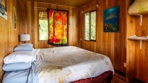 Wooden interior bedroom with colorful art and ocean view window.