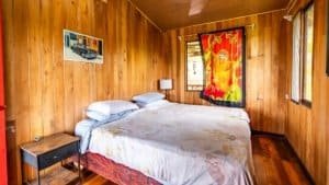 Wood-paneled bedroom with colorful artwork and large windows in Costa Rica.