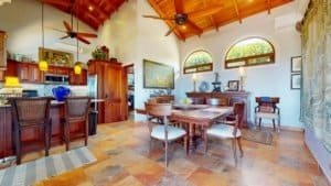 Spacious dining area with high wooden ceilings and large windows showing greenery.