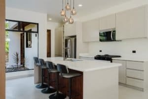 Contemporary kitchen with white cabinets, island, and pendant lighting in Costa Rica.