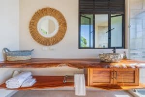 Rustic wooden bathroom vanity with a round mirror and stone sink in Costa Rica.