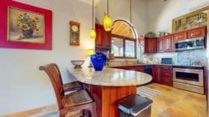 Tropical kitchen with wooden cabinets, granite counters, and modern appliances.