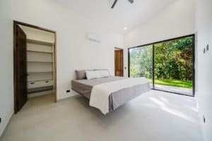 Bright bedroom with large window overlooking lush greenery in Costa Rica.