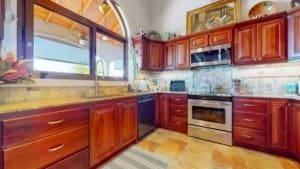 Warm kitchen with wooden cabinets, modern appliances, and a large window with a view.