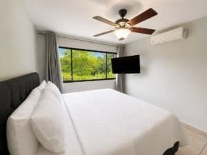 Comfortable bedroom with large window and ceiling fan in Dominical.
