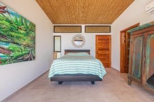Interior of a bedroom with a large bed, wooden accents, and colorful wall art.