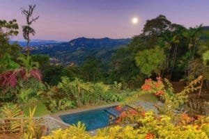 Scenic mountain view with pool and lush garden at sunset in Dominical.
