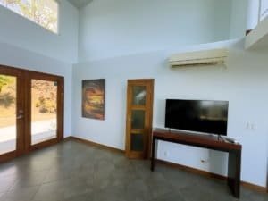 Bright living room with large windows, artwork, and a TV in Dominical.